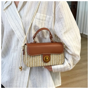 Dettaglio borsa in paglia intrecciata con patta in pelle marrone e chiusura dorata