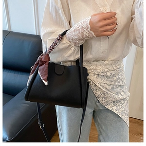 Dettaglio borsa a secchiello in pelle nera con foulard di seta sulla maniglia