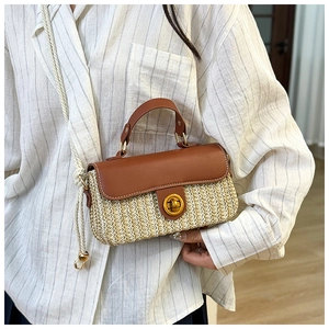 Dettaglio della borsa in paglia intrecciata con patta in pelle marrone e chiusura a girello oro