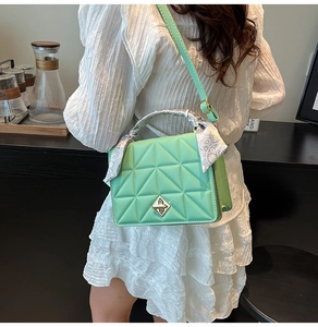Detail of mint green quilted bag with golden lock and silk scarf wrapped handle