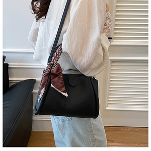 Dettaglio della borsa a secchiello in pelle nera con elegante foulard in seta