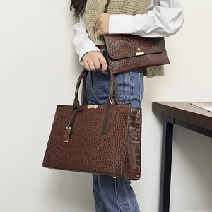 Detail of dark brown crocodile pattern tote bag set with matching envelope clutch bag