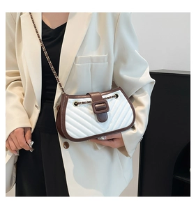 Detail of a quilted small crossbody bag with chain strap worn with an elegant suit
