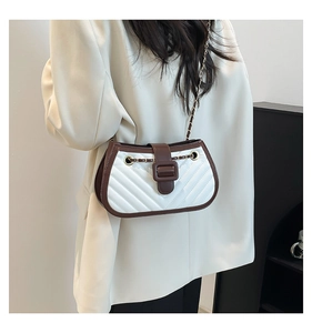 Detail of white quilted crossbody bag with brown leather accents and gold chain strap