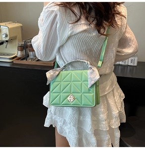 Detail of mint green quilted PU bag with scarf-wrapped handle and gold metal lock
