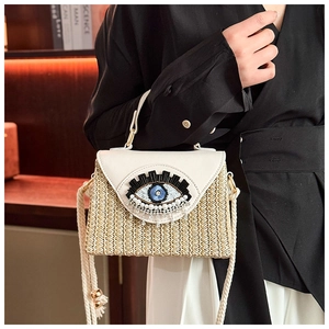 Dettaglio borsa in paglia con patta in pelle bianca ed emblema malocchio con cristalli