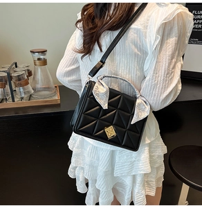 Detail of black quilted shoulder bag with gold turn-lock and paisley silk scarf decor