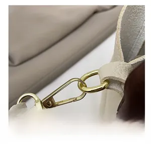 Dettaglio macro del gancio girevole in metallo dorato su borsa in pelle beige