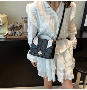 Detail of black quilted shoulder bag featuring silver clasp and vintage silk scarf handle