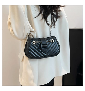 Detail of chevron quilted black crossbody bag with chain strap on beige blazer