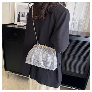 Detailed shot of shiny silver sequined shell bag with golden kiss-lock and chain strap