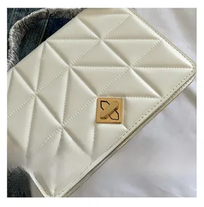 Detail of white quilted handbag with golden lock and silk scarf wrapped handle