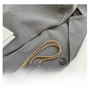 Detailed close-up of quilted gray fabric texture with gold chain strap and black button