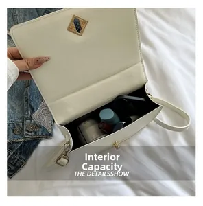Internal capacity of white shoulder bag with gold twist lock showing makeup storage space