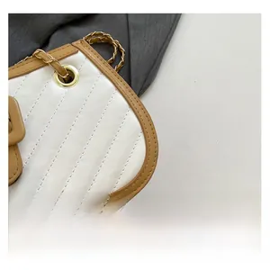 Detail of quilted leather handbag with gold grommets and chain woven shoulder strap