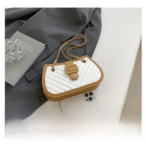 Detail shot of a quilted crossbody bag with golden chain strap on a blazer background