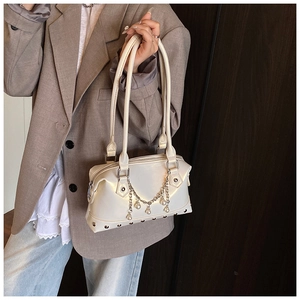 Detail of cream white tote bag featuring metallic rivets and elegant pearl chain ornament
