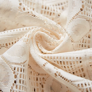 Gros plan d'un tissu de dentelle française aux motifs géométriques et texture crème