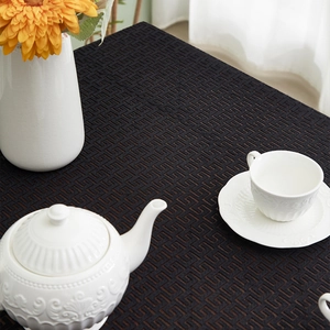 Detail of black geometric fret pattern on heavy cotton linen tablecloth with white ceramics