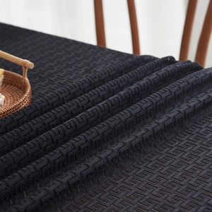Detail of black geometric jacquard knit fabric showing heavy texture and draped pattern