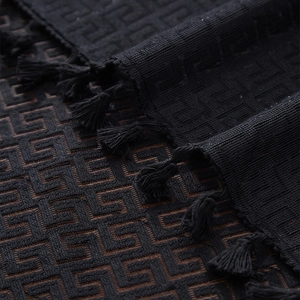 Macro shot of black tablecloth featuring Greek key jacquard pattern and fringe edge