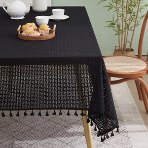 Detail of vintage black hollow lace tablecloth with retro geometric patterns and fringe