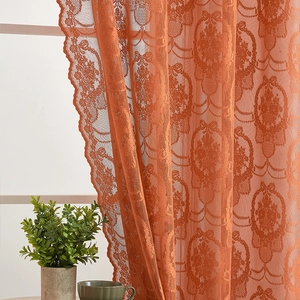 Close-up of burnt orange lace curtain featuring classic damascus floral pattern and scalloped edges