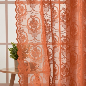 Close-up of caramel orange lace curtain with floral patterns and scalloped edges