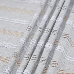Detailed close-up of French vintage striped tablecloth fabric with white knot embroidery
