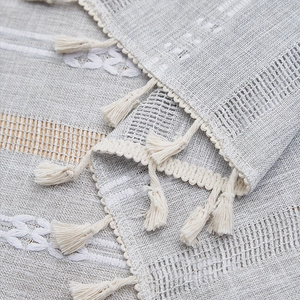 Close-up of hollowed-out embroidery and handmade tassels on cotton linen tablecloth