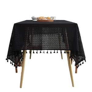 Black hollow Greek key tablecloth with delicate fringe on rectangular wooden table