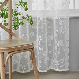 Detail of white French lace curtain featuring elegant rose patterns and scalloped edges