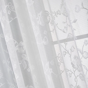 Macro shot of French lace curtain with delicate floral embroidery and sheer mesh texture