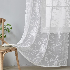 Detail of white French lace curtain with delicate rose embroidery and scalloped edges