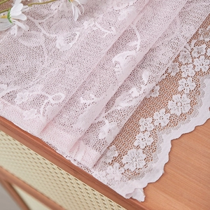 Detail of pink floral lace curtain fabric with elegant scalloped edges and mesh texture