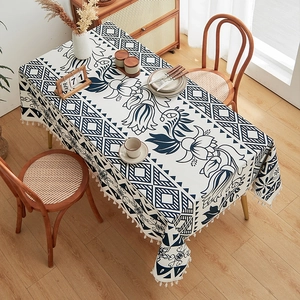 Close-up of bohemian linen tablecloth with blue floral patterns and white fringe edge