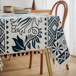Detail of bohemian linen tablecloth with navy floral patterns and cream tassels