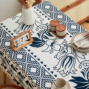 Detail of ethnic floral print linen tablecloth with navy blue patterns and cream tassels