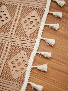 Close-up of bohemian hollow crochet tablecloth with elegant white fringe tassels