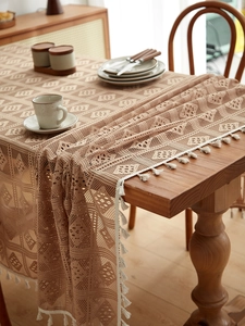Detailed close-up of bohemian crochet tablecloth featuring geometric lace and white tassels