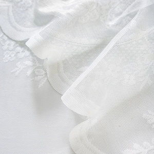 Detailed macro view of white French vintage lace curtain with delicate floral patterns