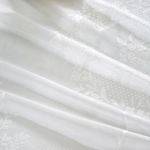 Detailed view of white floral lace fabric with delicate embroidery for door curtains