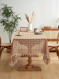 Detail of khaki lace tablecloth featuring geometric hollow weaving and white fringe