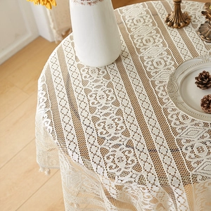 Detail of beige hollow-out lace tablecloth with tassels and intricate floral patterns