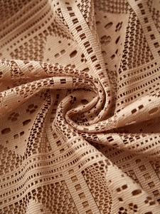 Macro detail of beige lace tablecloth showing intricate hollow geometric crochet patterns