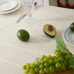 Detail of cream cotton linen tablecloth with leaf embroidery and rustic tassel edges