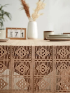 Detail of beige crochet tablecloth with geometric hollow patterns and woven texture