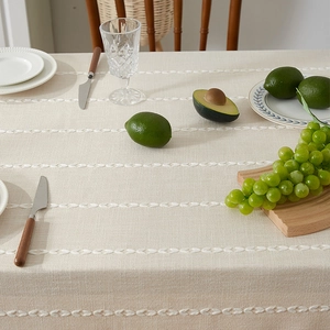 Detailed view of beige cotton linen tablecloth with woven wavy stripes and fringe texture