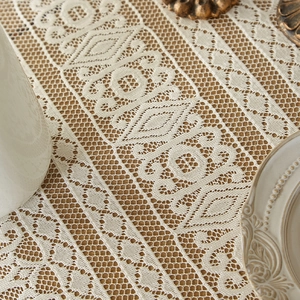 Close-up of bohemian ivory lace tablecloth with geometric hollow textures on dark wood
