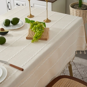 Detail of beige cotton linen tablecloth with white embroidery and fringe tassels
